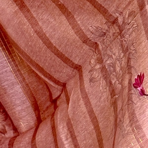 Op de afbeelding: Een close-up van een roze en witte gestreepte stof met een bloemenpatroon. De stof heeft een subtiele glans en een textuur.