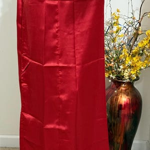 May include: A red satin underskirt with a gathered waistband. The skirt is long and flowing, and it is perfect for wearing under a saree or other traditional Indian clothing.