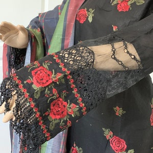 May include: Black embroidered dress with red roses and lace trim on the sleeves.