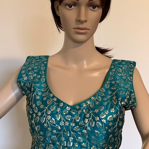 Puede incluir: Blusa azul turquesa sin mangas con bordado dorado y lentejuelas en un patrón floral.