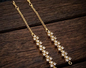 May include: A pair of long gold-tone chain earrings featuring a delicate link design that transitions into a vertical row of clear, round-cut sparkling stones. Each earring terminates in a small circular loop at the bottom and a hook at the top.