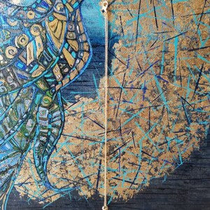 May include: Abstract painting of a bird with blue, gold, and teal geometric patterns. A delicate gold chain hangs from the bird's beak. The background features gold and teal brushstrokes on a dark blue canvas.