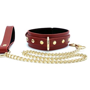 May include: A red leather choker with gold studs and a matching leash with a gold chain.