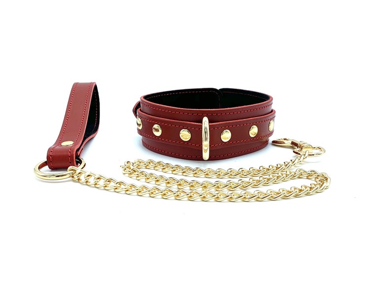 May include: A red leather choker with gold studs and a matching leash with a gold chain.