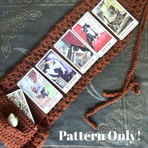 Könnte beinhalten: Eine rostfarbene gehäkelte Tarotkartenhülle mit Bindeband, die fünf Katzen-Tarotkarten mit den Aufschriften Eight of Cups, XVI The Tower, Seven of Cups, Page of Cups und Three of Pentacles zeigt, mit dem Text Pattern Only! am unteren Rand.
