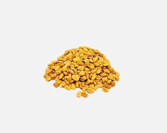 May include: A pile of yellow fenugreek seeds on a white background.