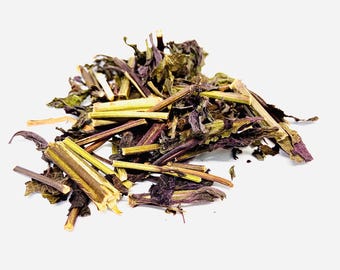 May include: A pile of dried botanical material consisting of dark purple and green leaves mixed with light tan, fibrous woody stems. The plant matter is fragmented and irregular in shape, showing a mix of deep violet and earthy olive tones.