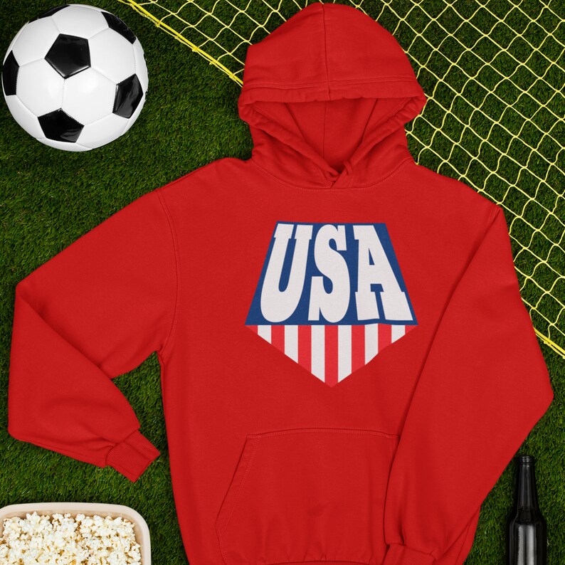 May include: Red hooded sweatshirt with a white, blue, and red USA graphic on the front.