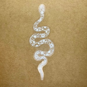 Könnte beinhalten: Weißer Vinyl-Aufkleber mit einer Schlange mit floralem Muster. Die Schlange ist spiralförmig zusammengerollt.