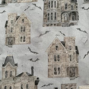 K&ouml;nnte beinhalten: Stoff mit einem sich wiederholenden Muster von Vintage-H&auml;usern mit Spuk-Optik in Beige-, Grau- und Braunt&ouml;nen. Silhouetten von Flederm&auml;usen sind &uuml;ber das Design verstreut. Die H&auml;user haben mehrere Fenster, T&uuml;ren und architektonische Details.
