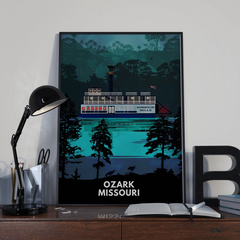 May include: A black and white illustration of a riverboat casino with the text "Casino" and "Missouri Belle" on the side. The boat is surrounded by trees and the text "Ozark Missouri" is at the bottom of the image.