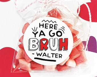 May include: A white circle sticker with black text that reads "Here Ya Go,  Bruh - Walter" with a red heart in the middle of the word "Bruh". The sticker is on a clear plastic bag filled with pink heart-shaped candies.