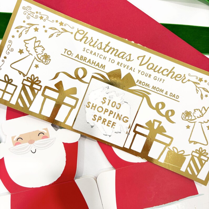 May include: A Christmas voucher with gold foil accents, featuring the text "Christmas Voucher" and "TO: ABRAHAM". The voucher has a scratch-off area revealing "$100 SHOPPING SPREE". Decorative elements include gift boxes and angels.