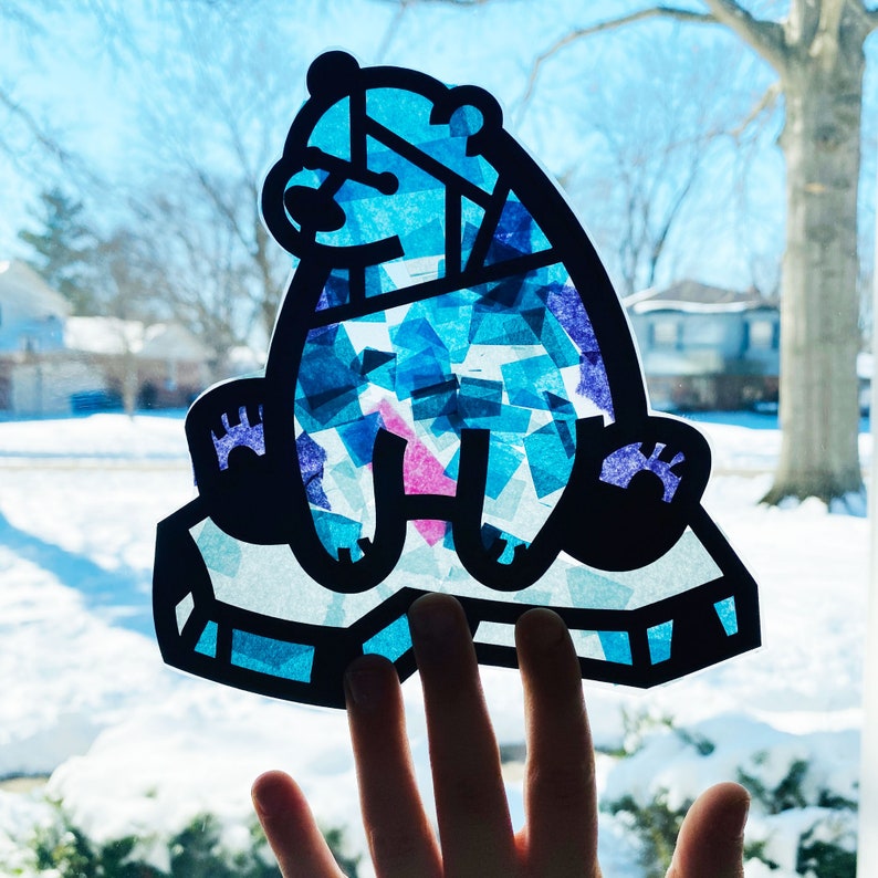 May include: A blue and purple stained glass bear craft on a white background. The bear is sitting on a blue and white ice-like surface.