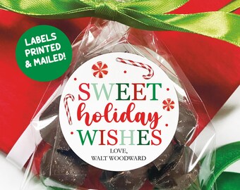 May include: A clear cellophane bag filled with dark chocolate candies, tied with a green ribbon. A round sticker on the bag reads "Sweet Holiday Wishes" in red and green, with candy cane and snowflake graphics. The text "Labels Printed & Mailed!" is on a green circle.