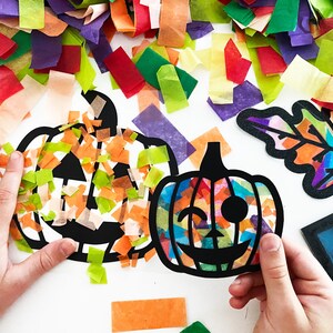 May include: Two black pumpkin-shaped paper cutouts filled with translucent, multi-colored tissue paper squares. One pumpkin features a winking face, while the other is partially covered in orange and green paper scraps. A leaf cutout is visible.
