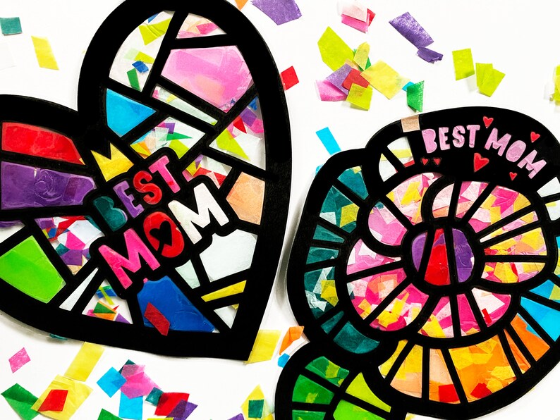 May include: Two colorful paper crafts, a heart and a flower, both with black outlines and filled with colorful tissue paper. The heart says "Best Mom" in pink letters with a small heart in the middle of the "O". The flower has a pink center and says "Best Mom" in pink letters with three small hearts above the text.