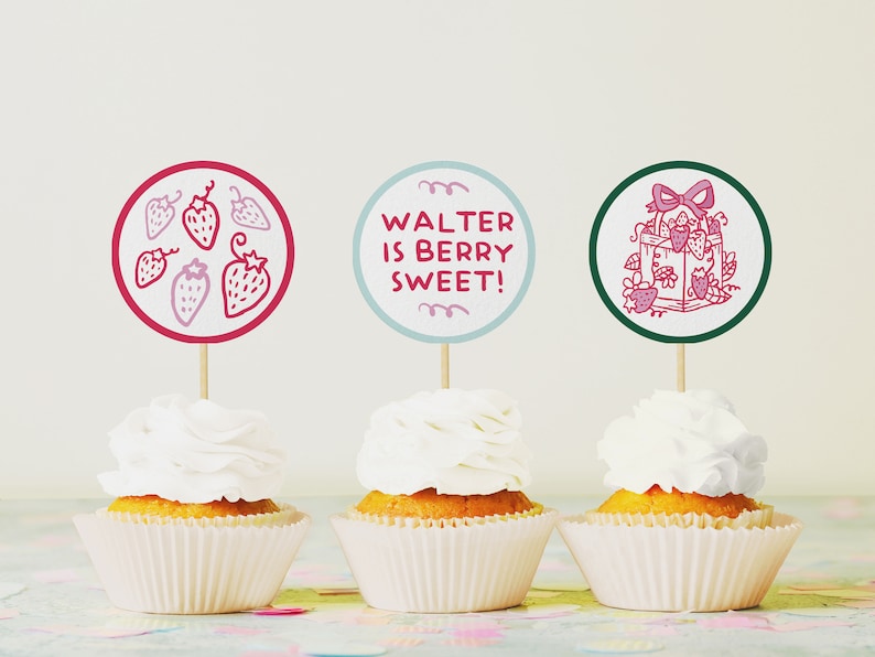 May include: Three cupcakes with white frosting and red and green circular toppers. The toppers have illustrations of strawberries and a gift box with a bow. The text on one topper reads "Walter is berry sweet!"