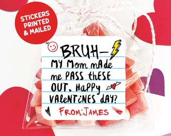 May include: A white card with a handwritten message that says "BRUH- MY Mom made me PASS THESE OUT. Happy VALENTINES DAY? FROM: JAMES" with a lightning bolt, a heart, and a smiley face. The card is in a clear plastic bag with pink heart-shaped candies.