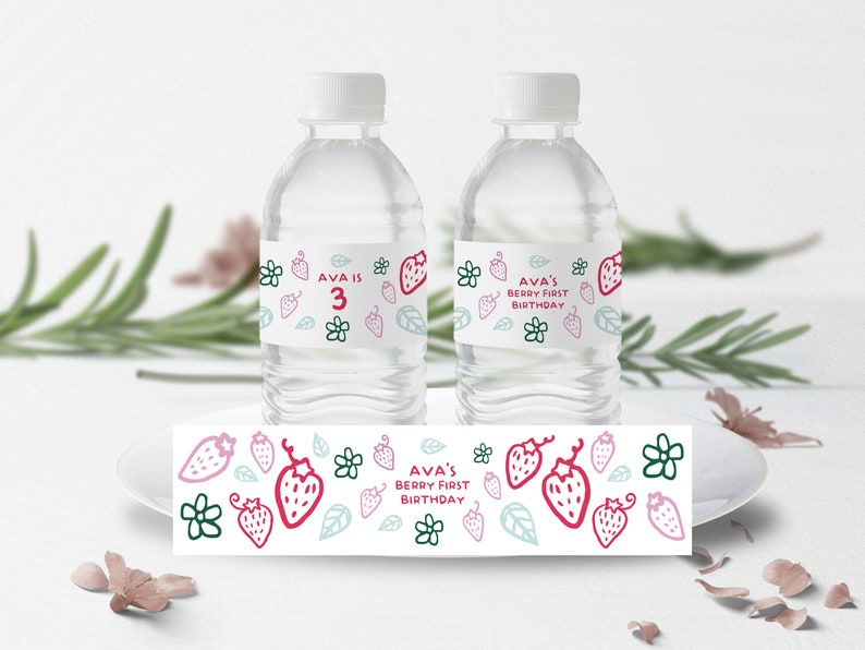 May include: Water bottle labels with a strawberry and floral design. The labels say "Ava is 3" and "Ava's Berry First Birthday".