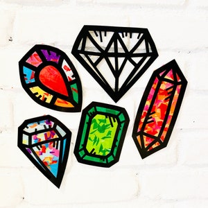 May include: Five colorful paper diamond shapes with black outlines. The diamonds are made of different patterned papers, including red, green, and orange.