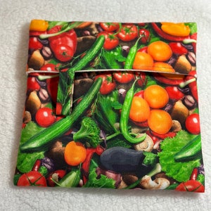 May include: A reusable food storage bag with a colorful print of various vegetables, including tomatoes, cucumbers, peppers, and mushrooms.