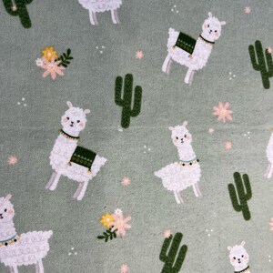 May include: A green fabric with a repeating pattern of white llamas, green cacti, and pink and yellow flowers.