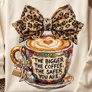 May include: A cream-colored long-sleeve sweatshirt featuring a graphic of a coffee cup with latte art, topped with a large leopard print bow. The cup displays the text, "THE BIGGER THE COFFEE, THE SAFER YOU ARE," and is adorned with a charm of a handbag.
