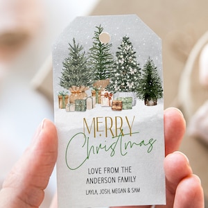 May include: A Christmas gift tag featuring a watercolour illustration of fir trees and wrapped presents. The tag has the words "MERRY CHRISTMAS" in gold and green script, with a family name and names below.