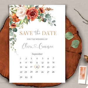 May include: Save the Date wedding invitation with a watercolor floral design in shades of orange, white, and green. The invitation features a calendar with the date circled in gold. The text reads "Save the Date for the Wedding of Olivia & Cameron, September".