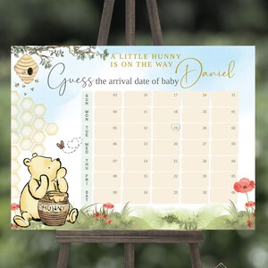 Può includere: Un cartello per un gioco di baby shower a tema Winnie the Pooh con uno sfondo acquerellato blu e verde. Il cartello dice "Indovina la data di arrivo del bambino Daniel". Un calendario con un barattolo di miele e Winnie the Pooh sono sul cartello.