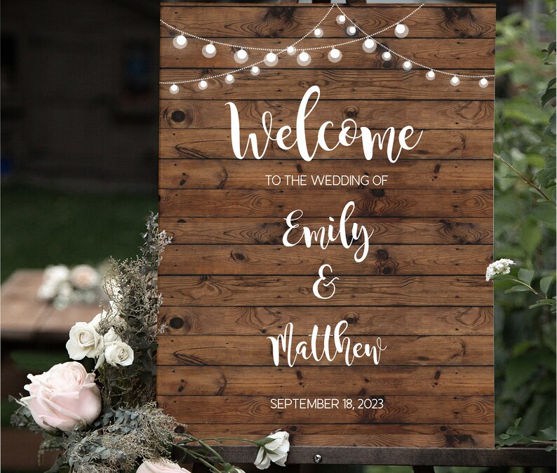 May include: Rustic wooden wedding welcome sign with string lights, featuring the text "Welcome to the wedding of Emily & Matthew" and the date "September 18, 2023".