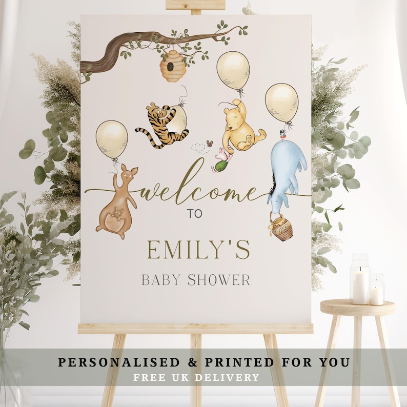 May include: A baby shower welcome sign with illustrations of Winnie the Pooh characters, balloons, and a honey pot. The sign says "Welcome to Emily's Baby Shower". The sign is displayed on a wooden easel.