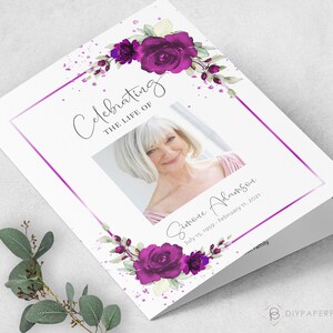 May include: A white folded card with a purple floral design and a photo of a woman. The text "Celebrating the Life of Simone Adamson July 15, 1959 - February 11, 2021" is printed on the card.