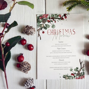 May include: A Christmas menu with a watercolor design of red berries, green leaves, and a white background. The menu includes a starter, main course, and dessert. The text reads: "CHRISTMAS Menu".