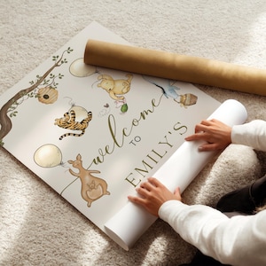 May include: A personalised welcome sign with the text "welcome to EMILY'S" in green script. The sign features watercolour illustrations of cartoon animals, balloons, and a tree branch. A rolled-up poster is next to the sign.