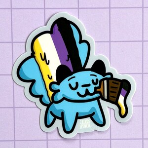 May include: A blue cartoon creature with a black and white face is holding a paint tube with the colors of the non-binary pride flag. The paint tube is dripping paint.