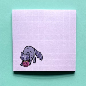May include: A purple sticky note with a grid pattern features a cartoon raccoon drinking from a pink mug that says "Girl Boss".