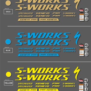 K&ouml;nnte beinhalten: Aufkleber-Set mit dem "S-WORKS"-Logo in Gold, Blau und Gelb. Enth&auml;lt den Text "SPECIALIZED" und "KENEVO FSR". Das Set enth&auml;lt auch kleine Aufkleber mit Gr&ouml;&szlig;enangaben: M, S und L.