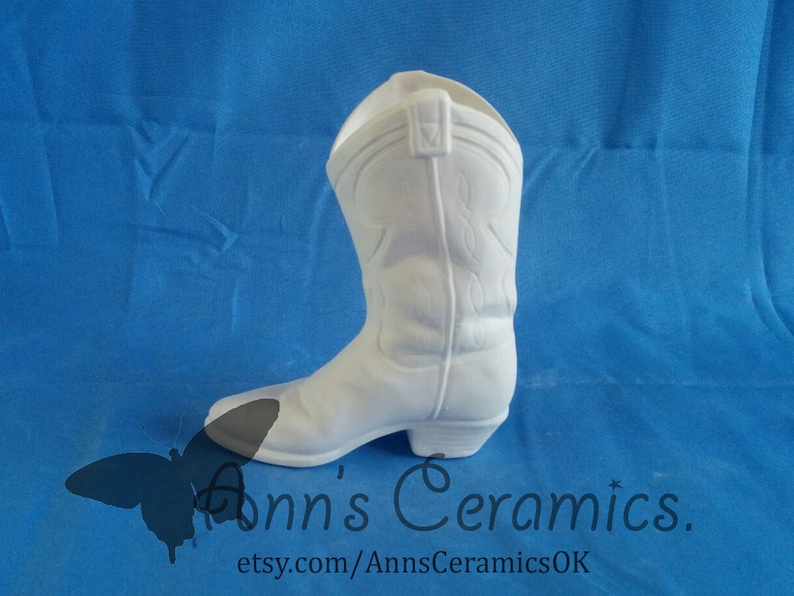 May include: White ceramic cowboy boot planter. The boot is a traditional style with a pointed toe and a high heel. It is a great way to add a rustic touch to your home decor.