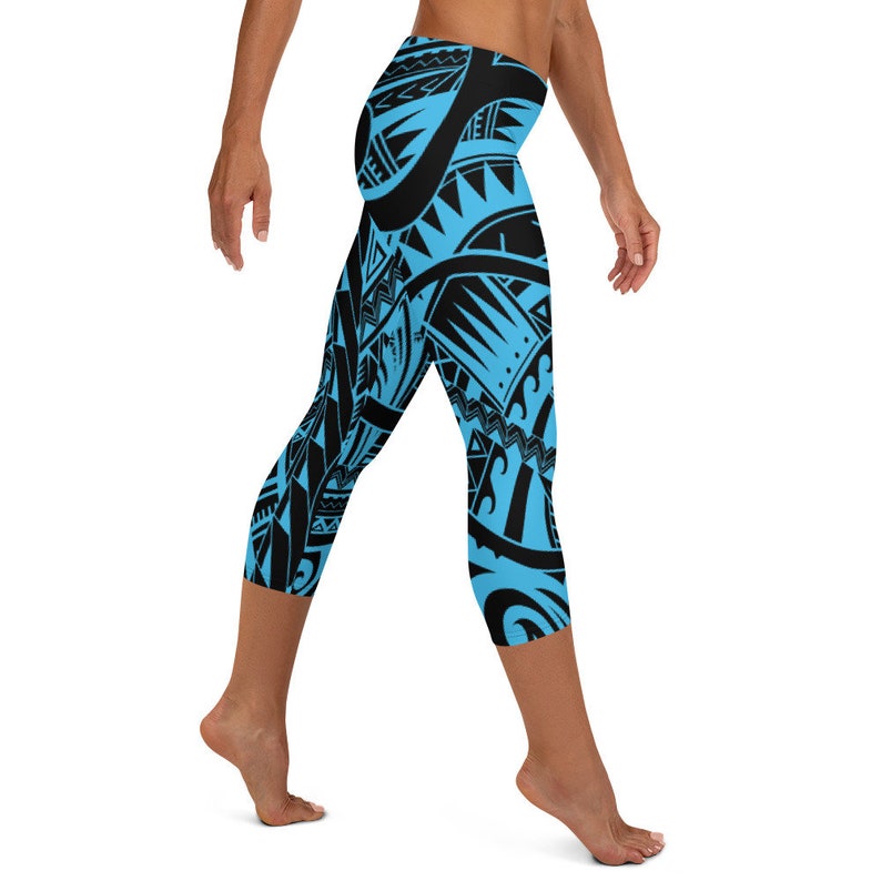 May include: Blue and black capri leggings with a tribal pattern. The leggings feature a repeating design of geometric shapes and lines in black against a bright blue background. The capri length ends just below the knees.
