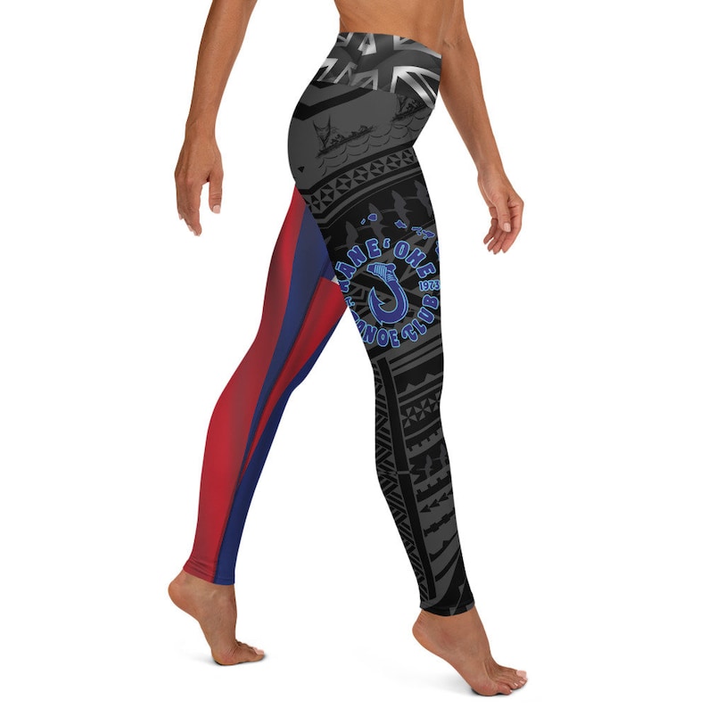 May include: High-waisted leggings with a unique design. The leggings feature a color block design with red and blue on one leg and a black and gray tribal pattern on the other. The leggings have the text "Kane'ohe Canoe Club 1973" in blue.
