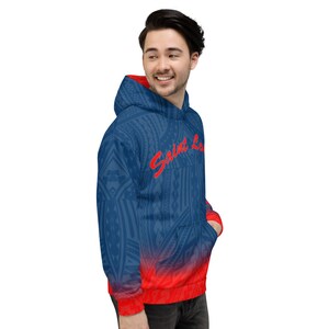 May include: Blue hoodie with a red interior and a red-to-blue gradient at the bottom. The hoodie features a tribal pattern and the name "Saint Louis" in red script across the chest. It has a hood and a front pocket.