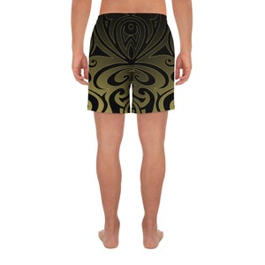 May include: Black and gold athletic shorts with a symmetrical, swirling design. The shorts have a gradient effect, transitioning from black at the top to gold at the bottom. The shorts are designed for athletic activities.