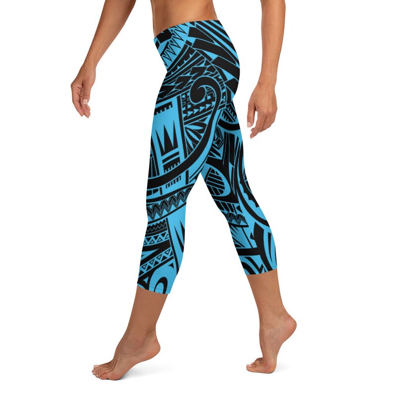 May include: Blue and black patterned leggings. The leggings feature a repeating tribal design in black against a light blue background. The leggings are cropped at the calf.