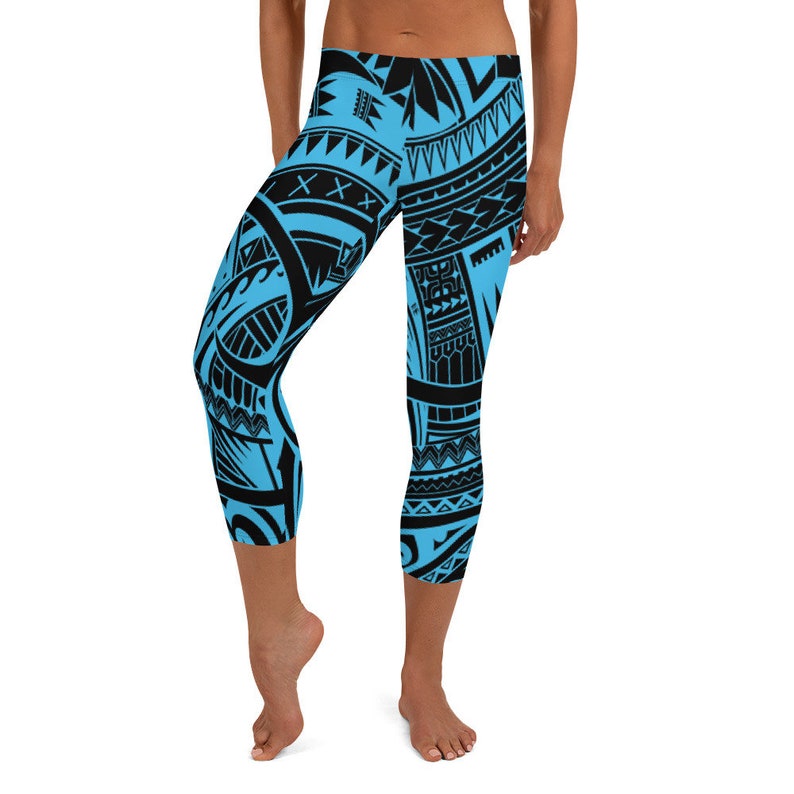 May include: Cropped leggings featuring a striking black tribal pattern against a vibrant blue background. The leggings have a high waist and a capri length, offering a comfortable fit. The design incorporates geometric shapes and lines, creating a bold and eye-catching look.