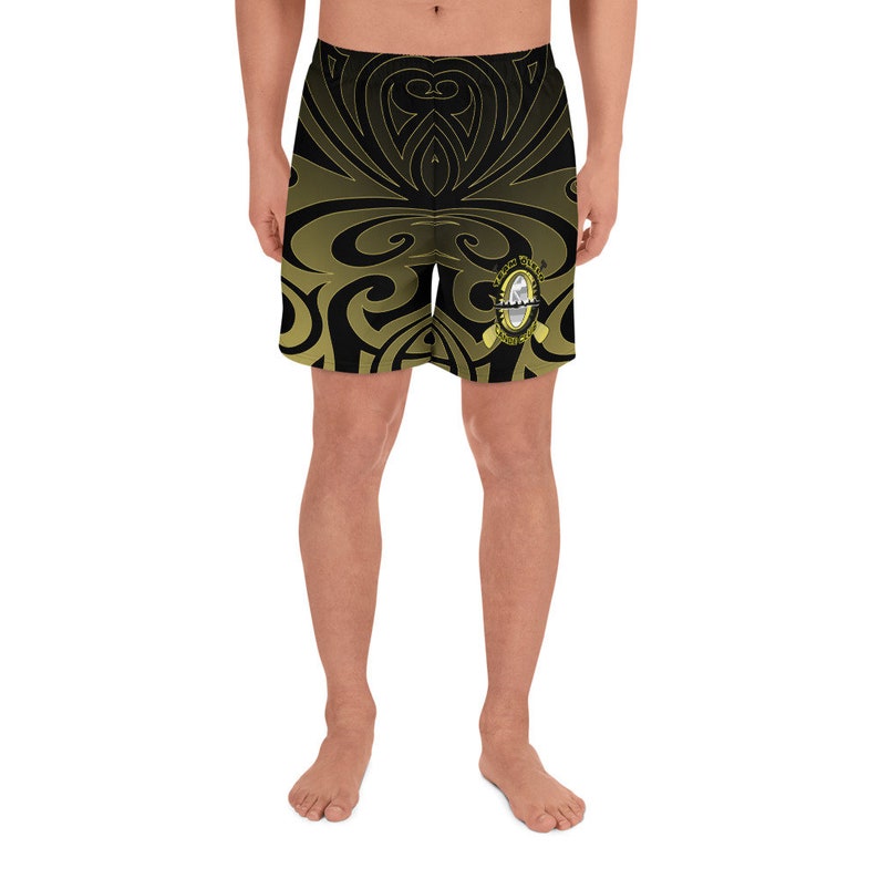 May include: Black and gold athletic shorts with a tribal design. The shorts feature a repeating pattern of swirling shapes and a logo on the right leg. The shorts are made of a lightweight material.