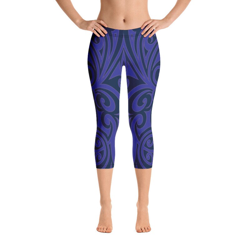 May include: Blue and navy capri leggings with a repeating, swirling pattern. The leggings are knee-length and form-fitting, featuring a dark blue design against a lighter blue background. The overall style is athletic and suitable for various activities.