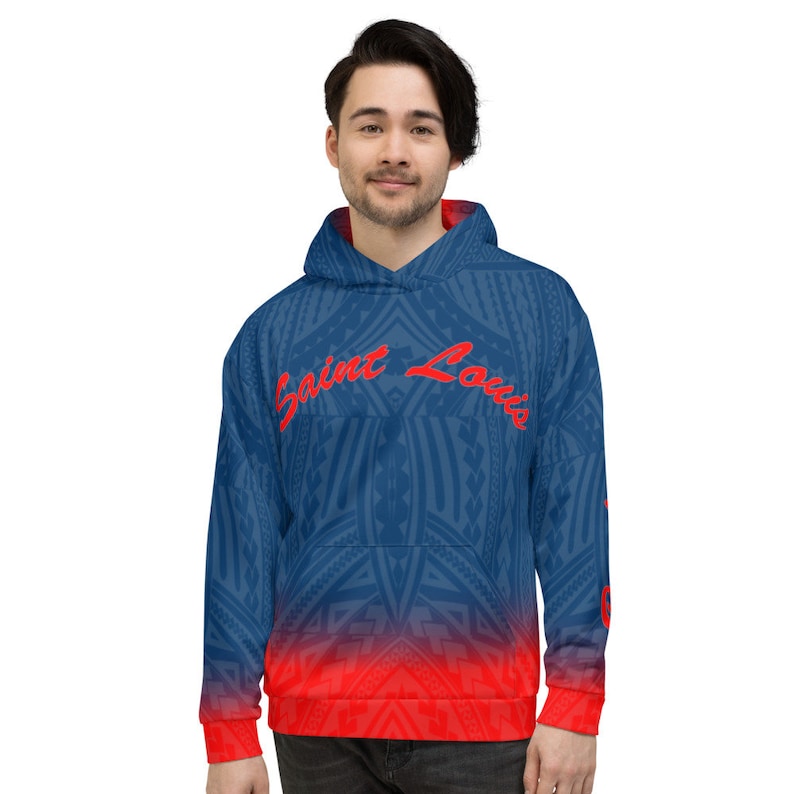 May include: A blue hoodie with a red and blue tribal pattern and the text "Saint Louis" in red script. The bottom of the hoodie and the cuffs are red. The hoodie has a front pocket and a hood.
