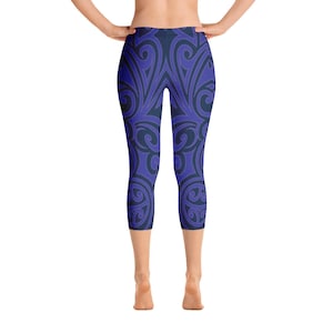 May include: Blue and navy capri leggings with a repeating, swirling pattern. The leggings are form-fitting and reach the mid-calf. The design features a symmetrical arrangement of curved lines and shapes, creating a visually appealing and dynamic look.